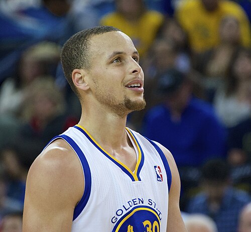 Stephen Curry looking upward in a Golden State Warriors uniform in 2014. Player photograph, not card artwork.